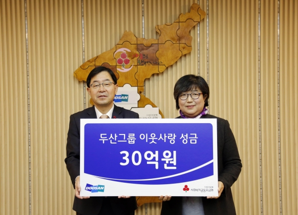 박완석 ㈜두산 부사장(왼쪽)이 김연순 사회복지공동모금회 사무총장에게 성금을 전달하고 기념촬영을 하고 있다. 제공=두산그룹.