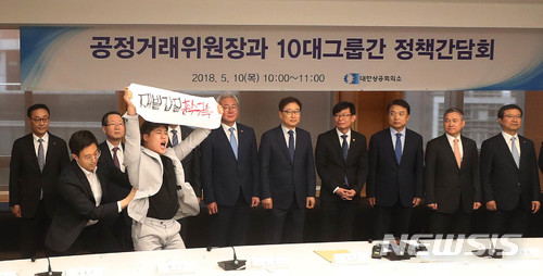 【서울=뉴시스】추상철 기자 =공정거래위원장과 10대그룹간 정책간담회가 열린 10일 오전 서울 중구 대한상공회의소에서 김상조 공정거래위원장을 비롯한 10대그룹 경영진이 기념촬영을 하는 중 금속노조 조합원이 '재벌갑질 총수구속'을 외치며 난입하고 있다. 2018.05.10. scchoo@newsis.com [사진=뉴시스]