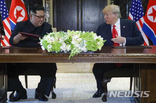 도널드 트럼프 미국 대통령과 김정은 북한 국무위원장이 12일 싱가포르 센토사 섬 내 카펠라 호텔에서 합의문에 서명한 후 웃고 있다. 2018.08.12 [싱가포르=AP/뉴시스]