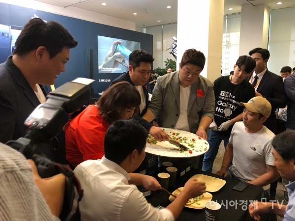 '맛있는녀석들' 팀이 지름 60cm의 대형피자를 SKT 갤럭시노트9 사전예약 가족고객들에게 나눠주고 있다.