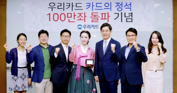 30일 우리카드 본사에서 진행된 '카드의정석' 100만좌 돌파 기념식에서 정원재 우리카드 사장(왼쪽에서 다섯번 째)이 김현정 한국화가(왼쪽에서 네번째)에게 감사의 표시로 기념카드를 전달하고, 상품개발에 참여한 유공직원 5명과 함께 기념 촬영을 하고 있다. [사진=우리카드]