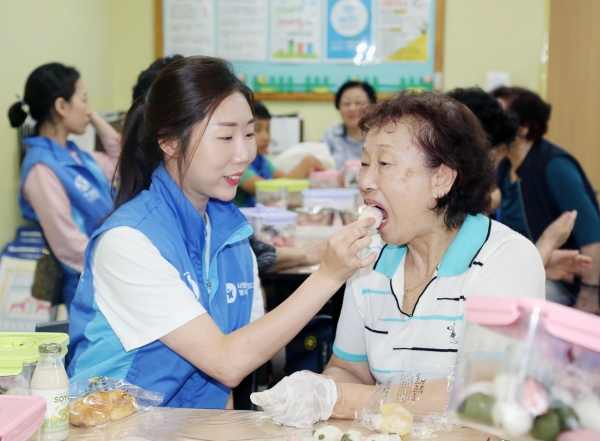 신한생명 직원봉사자가 어르신에게 함께 만든 송편을 시식하고 있다. [사진=신한생명]