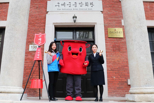 CJ대한통운은 연말 구세군의 자선모금 활동에 사용되는 자선냄비, 핸드벨, 저금통, 의류 등 자선모금 물품 1000여개의 배송을 후원한다고 29일 밝혔다. CJ대한통운 직원(왼쪽)과 구세군 직원이 구세군 캐릭터인 '따끈이'와 함께 기념촬영을 하고 있다 [사진=CJ대한통운]