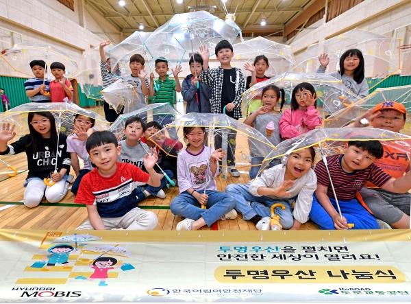 서울 고산초등학교 학생들이 현대모비스가 배포한 투명 우산을 들고포즈를 취하고 있다. 현대모비스는 올해 학교 방문, 개인사연 신청 등을 통해 10만 개 이상의 투명 우산을 배포하며, 2010년부터 배포한 투명 우산은 올해 100만개를 돌파한다 [사진=현대모비스]