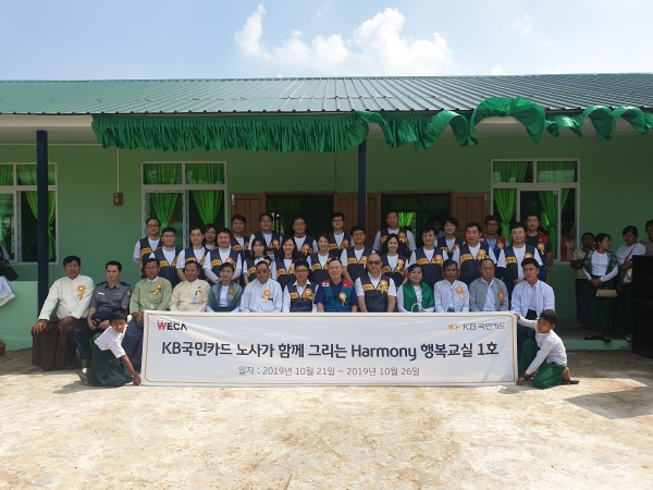 지난 24일 미얀마 양곤 ‘쉐비다 제17초∙중학교’에서 열린 다목적 교실 개소식에서 이경진 전국사무금융서비스노동조합 KB국민카드지부장(앞줄 왼쪽에서 7번째)과 우모쪼아웅‘쉐비다 시장’(앞줄 왼쪽에서 6번째) 등 현지 관계자들과 KB국민카드 노사 공동 해외 봉사단이 기념 촬영을 하고 있다.  [사진=KB국민카드]
