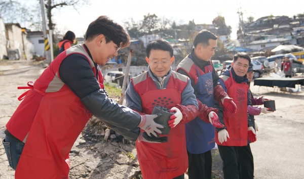 롯데건설 하석주 대표(왼쪽에서 두 번째)가 샤롯데 봉사단원들과 함께 연탄을 나르고 있다.
