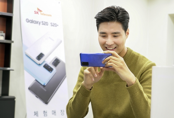 SK텔레콤 홍보모델이 T월드 매장에서 갤럭시S20 플러스 아우라 블루 모델을 써보고 있다. SK텔레콤은 27일부터 갤럭시S20 개통을 시작한다. [사진제공=SK텔레콤]