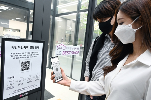 LG전자가 26일부터 국내 가전회사 가운데 처음으로 무인매장을 운영한다. 모델들이 매장에 들어가기 위해 입구에서 QR코드를 스캔해 본인 인증 절차를 진행하고 있다. [사진: LG전자 제공]