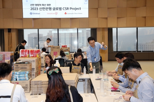 신한은행 본점에서 진행된 ‘Swith Global CSR 프로젝트’ 첫 행사에서 서승현 신한은행 글로벌사업그룹 부행장(첫번째줄 가운데), 선발 장학생, 베트남·캄보디아 대사관 직원 등 관계자들이 봉사활동을 하고 기념촬영하는 모습. [사진=신한은행]