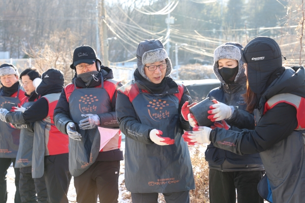 <롯데건설 박현철 부회장(오른쪽 세번째)과 배우 정애리(오른쪽 두번째)가 임직원들과 함께 연탄을 나르고 있다.>