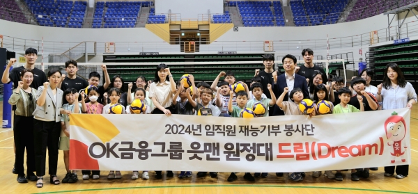 읏맨 프로배구단 홈구장인 ‘안산시 상록수 체육관’에서 진행한 금융교육 및 배구교실 수업을 마친 후 OK금융그룹 임직원들과 읏맨 프로배구단 선수들이 돌봄아동들과 함께 단체촬영을 하고 있다. [사진제공=OK금융그룹]