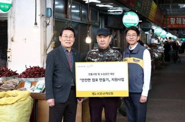 지난 18일 의정부제일시장 안전점검 현장에서 윤희승 KB손해보험 경영전략본부장(오른쪽)이 조진식 의정부제일시장 번영회장(왼쪽), 안전점검을 받은 소상공인과 기념사진을 찍고 있다. [사진=KB손해보험]